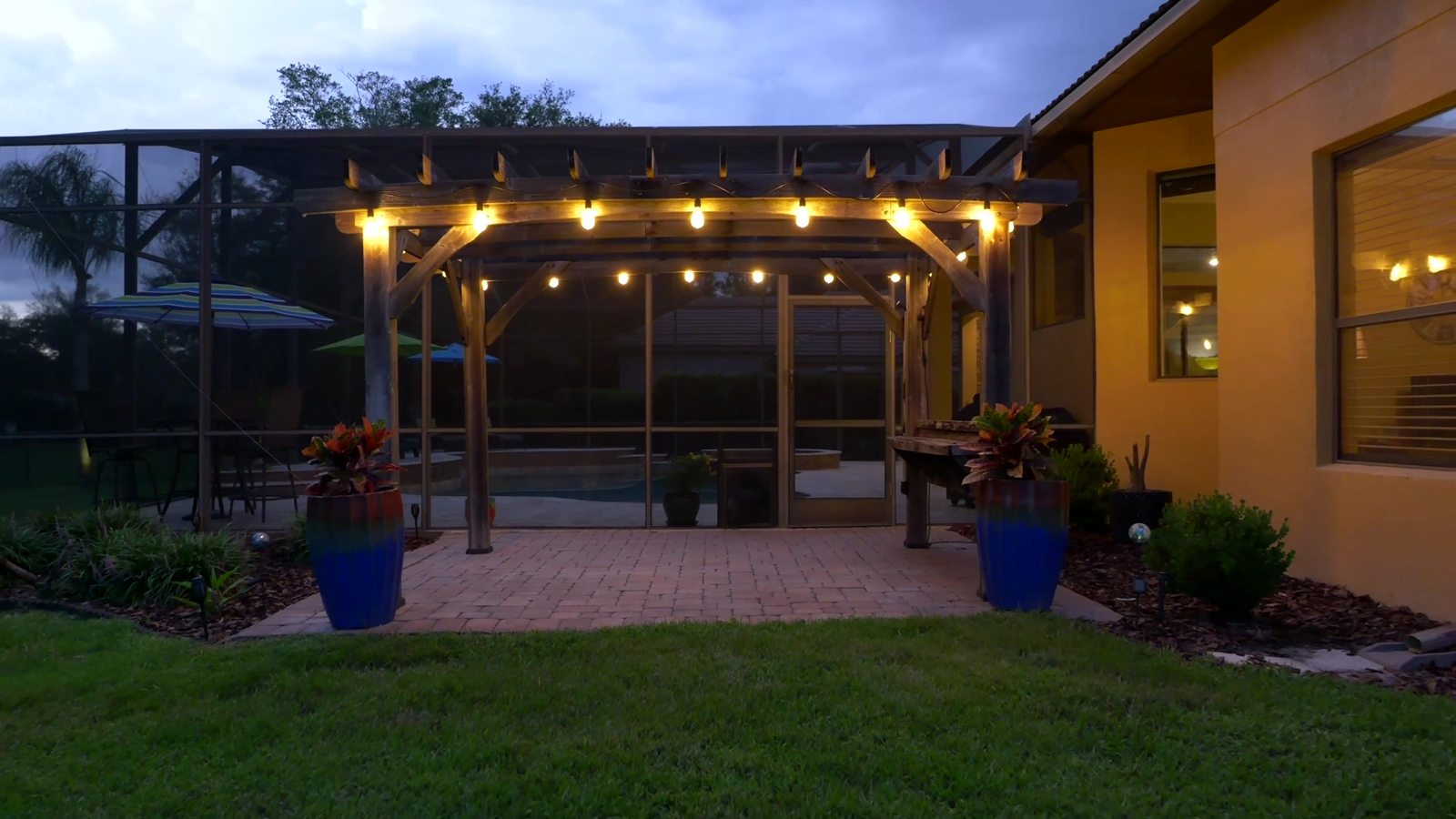 Covered lanai and pool glowing at twilight behind the Sanford luxury home
