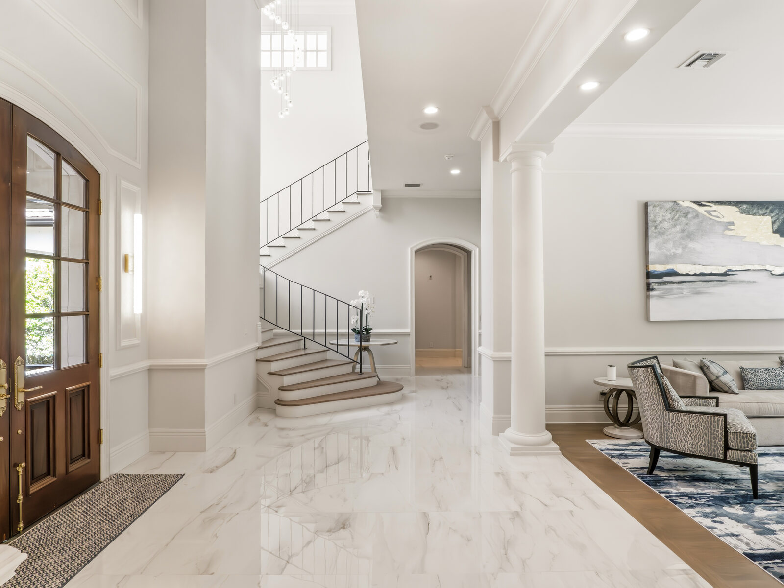Grand foyer with stone columns, coffered detailing, marble floors and a curved staircase inside the Isleworth estate
