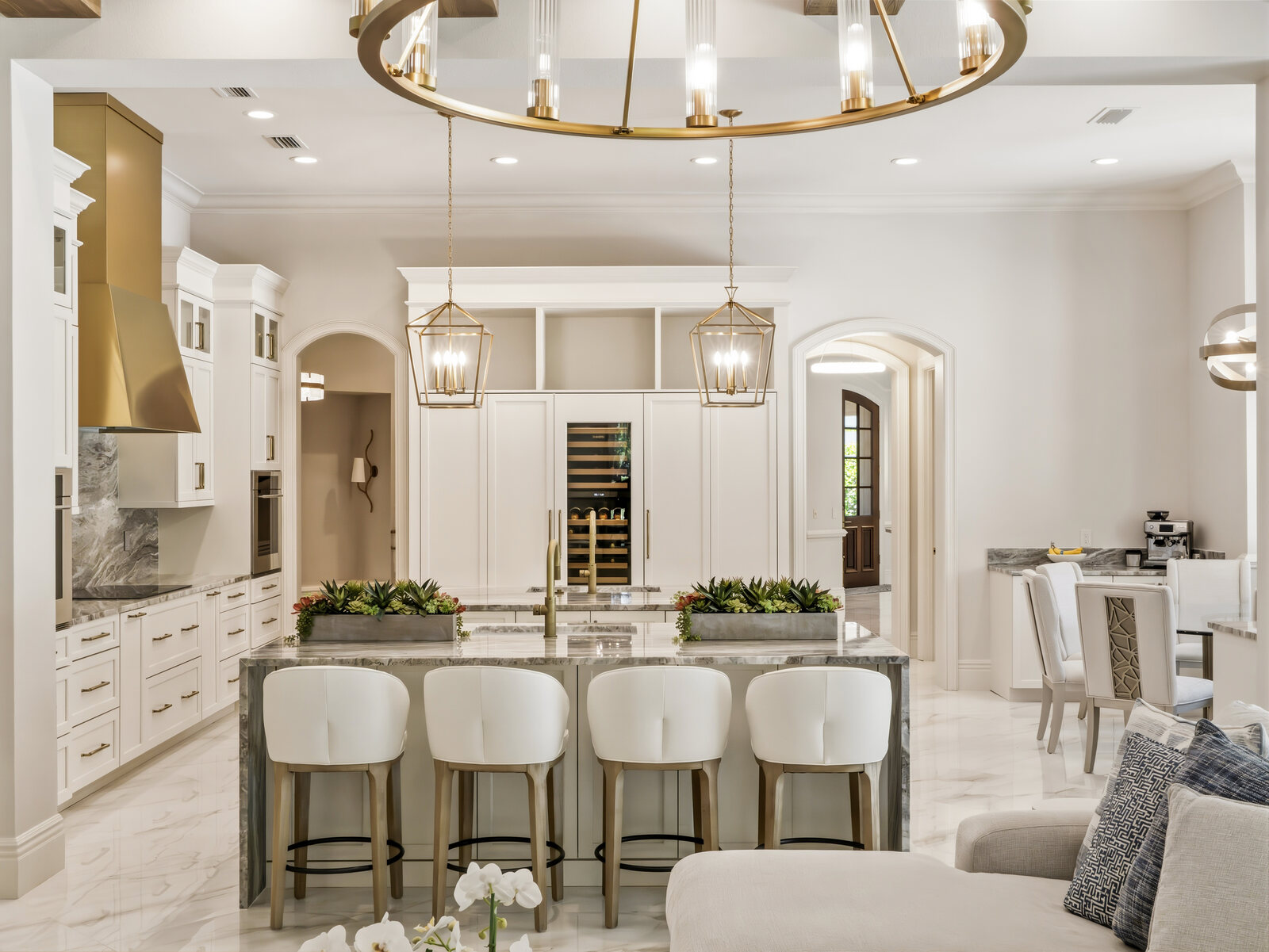 Gourmet kitchen with a waterfall marble island, brass fixtures, custom cabinetry and statement range hood in the Isleworth estate