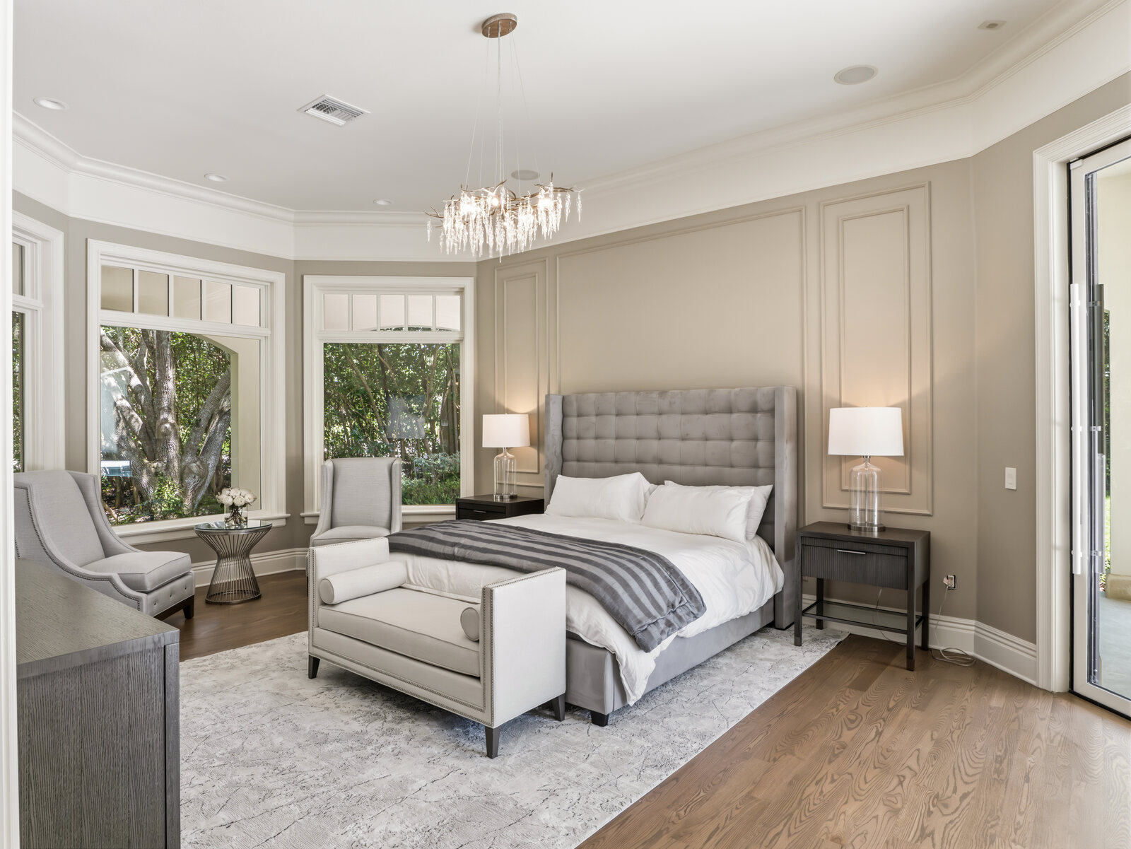 Primary bedroom suite with an upholstered bed, sitting area and doors to the outdoors