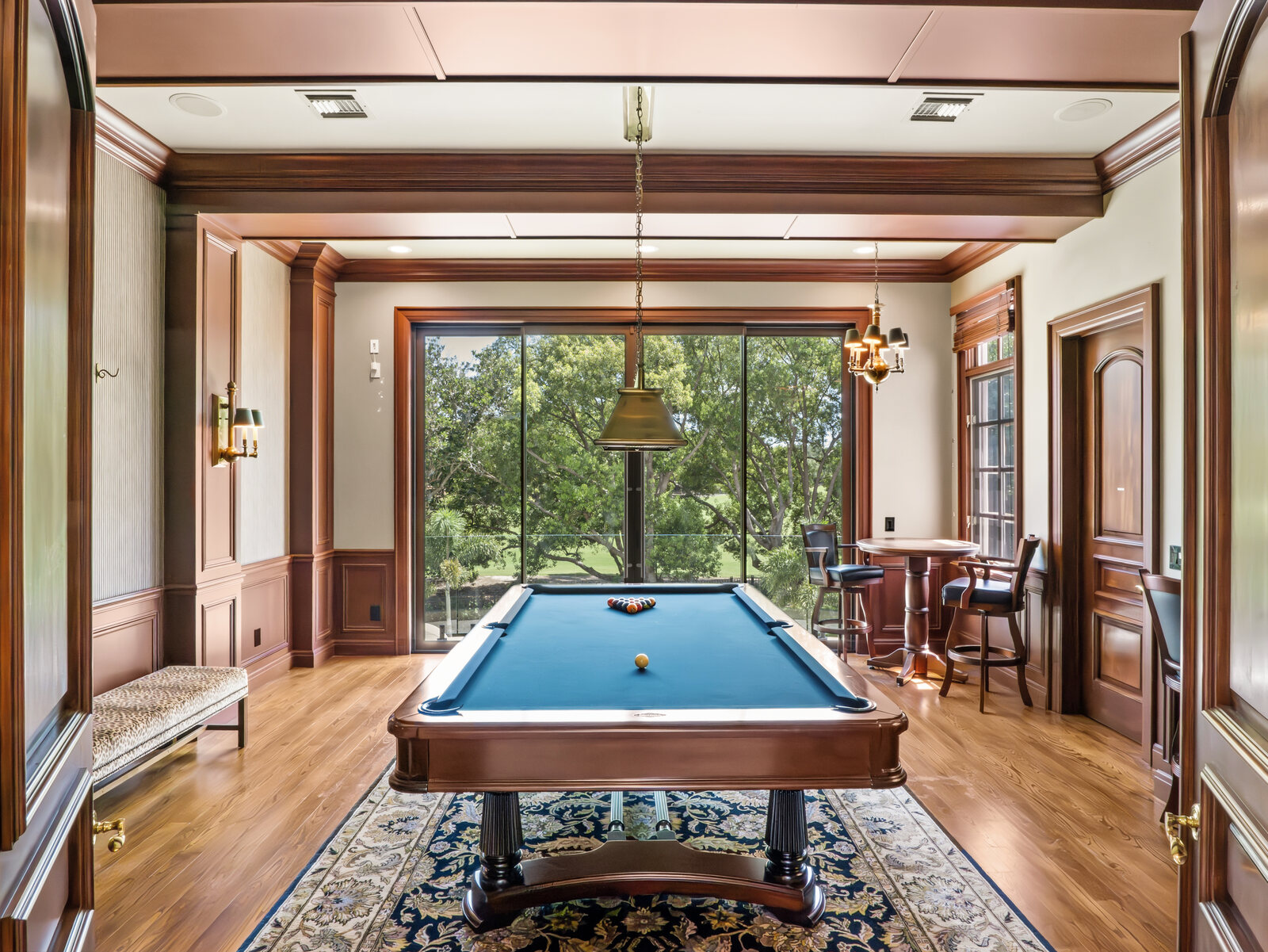 Wood-paneled billiards and game room with a pool table, custom millwork and French doors in the Isleworth estate