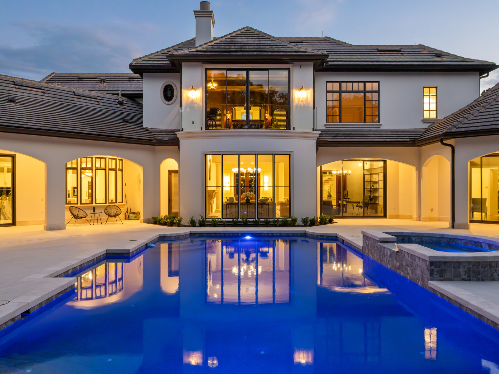 The Isleworth estate at twilight with the pool glowing and warm light in the windows