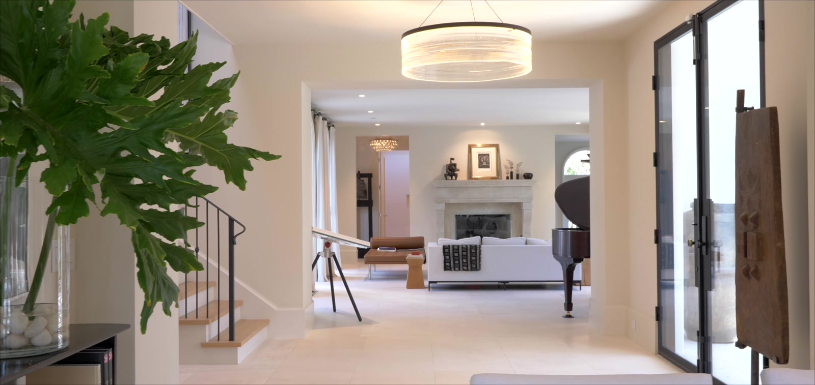 Grand living room with a stone fireplace, grand piano and limestone floors inside a Snell Isle estate