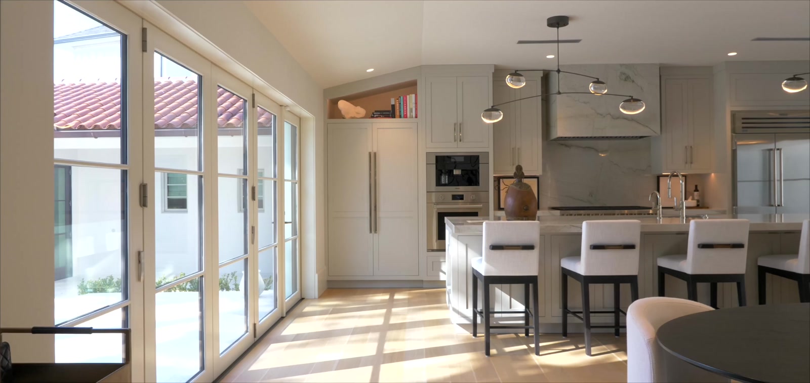 Chef's kitchen with a book-matched marble island and range hood, custom cabinetry and professional appliances